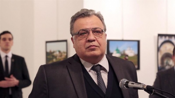 Büyükelçi açılışta konuşurken takım elbiseyle, sivil olarak törene katılan katili arkasında onu dinliyordu...